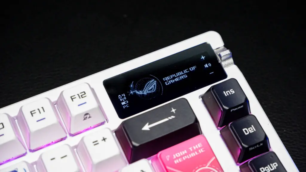 An Asus ROG Azoth X gaming keyboard on a desk with wrist rest and lighting enabled.