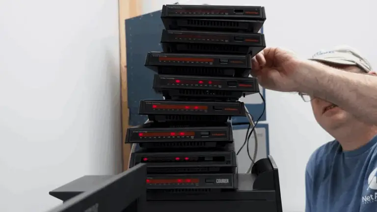 A number of black 56 Kbps dial-up modems stacked on top of eachother, red lights blinking.