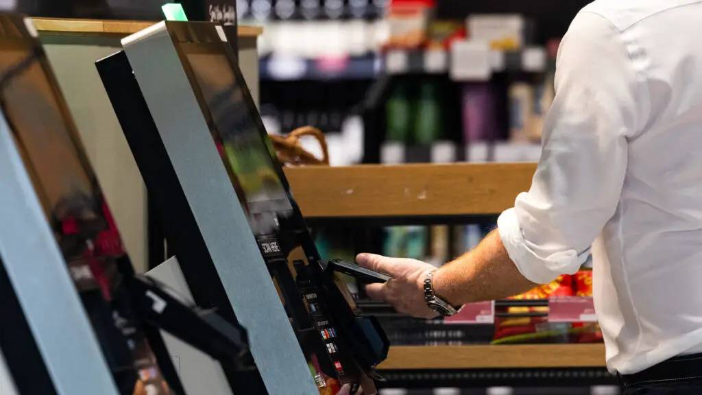 A photo of a customer at a UK Marks and Spencer store, using a phone to pay for shopping goods.
