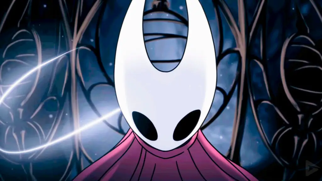 A screencap of Hollow Knight: Silksong's opening cutscene. A close-up shot of protagonist Hornet moments before she breaks out of a metal cage. Her curved white mask and red cloak are lit up as a glowing strand of silk surrounds her.