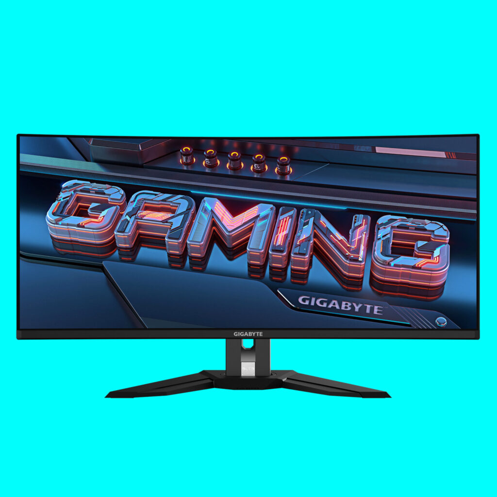 An image of a Gigabyte MO34WQC2 ultrawide OLED gaming monitor against a bright teal background.