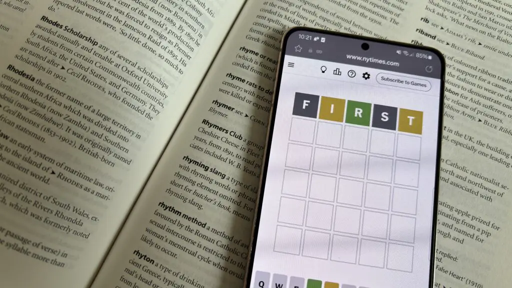 A phone playing Wordle set on top of a dictionary