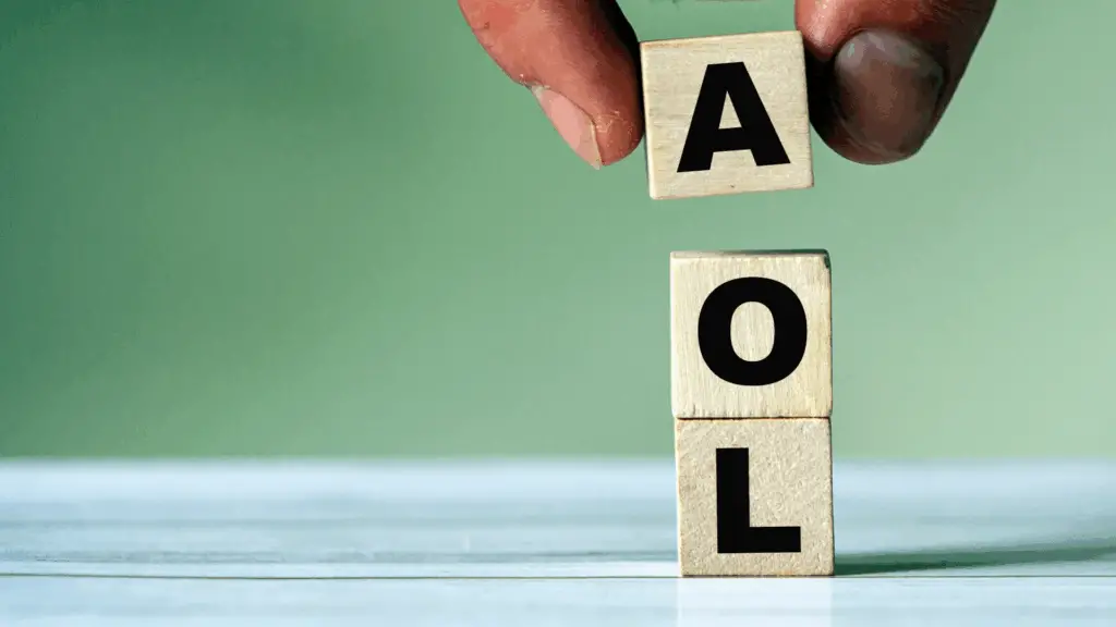 A stock photo of a hand placing a wooden block to spell out the initialism 'AOL'