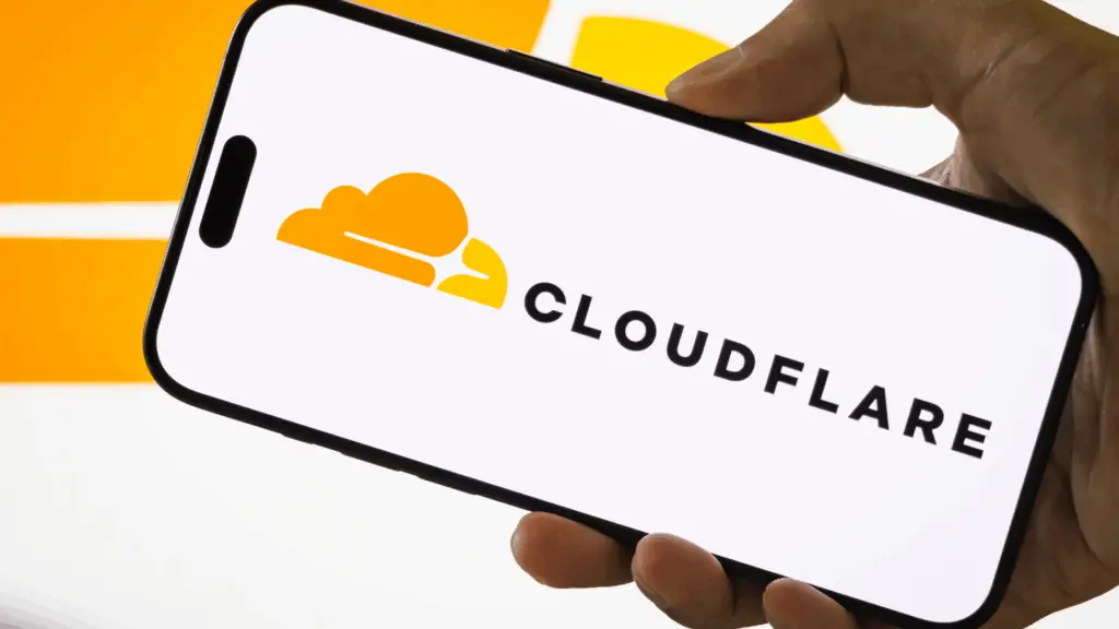 Person holding a smartphone displaying the Cloudflare logo during an outage.