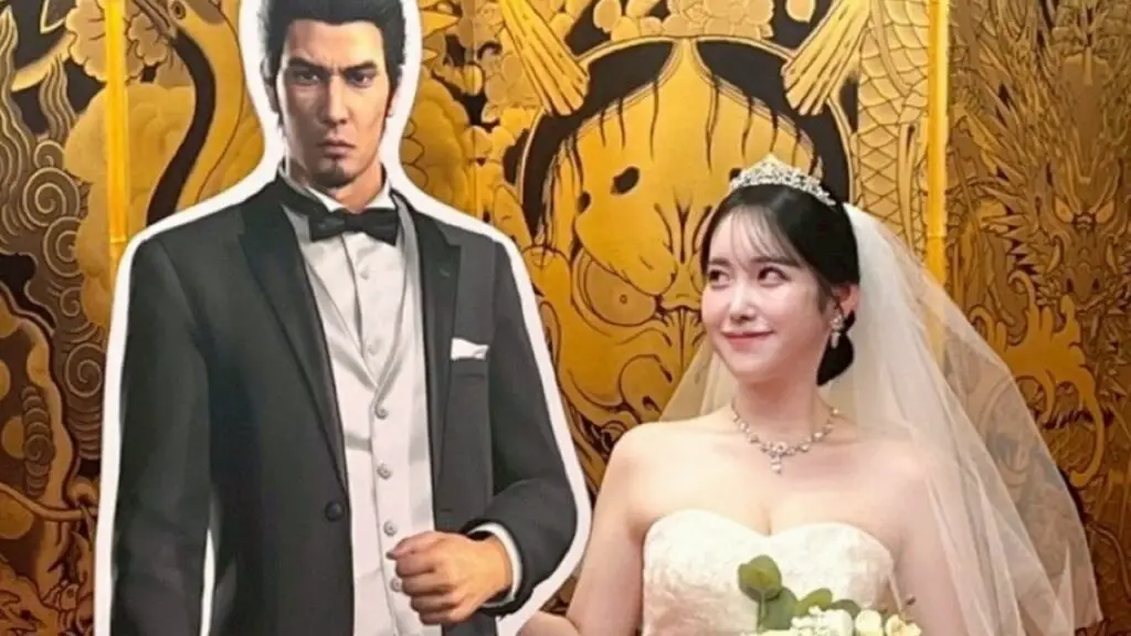 Real woman in wedding dress looking lovingly at cardboard cutout of Kazuma Kiryu.