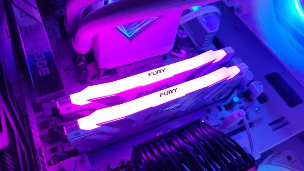 Two sticks of Kingston Fury DDR5 RAM in a gaming PC, lit up in pink