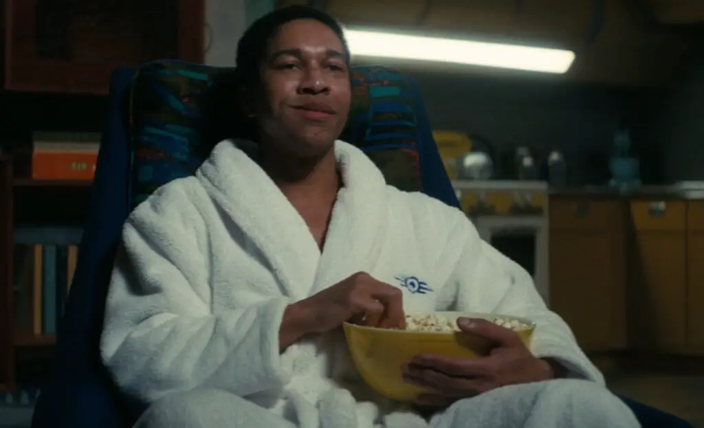 Maximus, a character from the Fallout TV show, watching television with popcorn in a reflective moment.