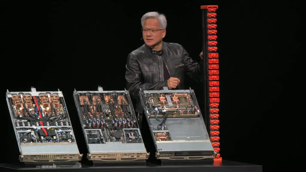 An image of the live presentation broadcast by Nvidia at Computex 2025, where CEO Jen-Hsun Huang holds an NVLink Fusion spine next to three Nvidia rank units.