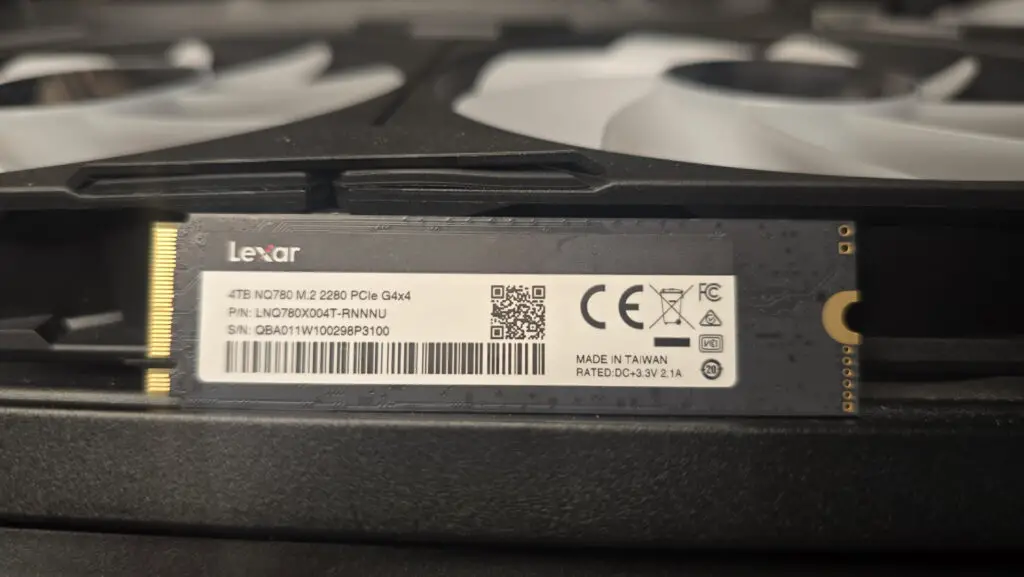 A Lexar NQ780 SSD installed inside a gaming PC and on top of a graphics card.