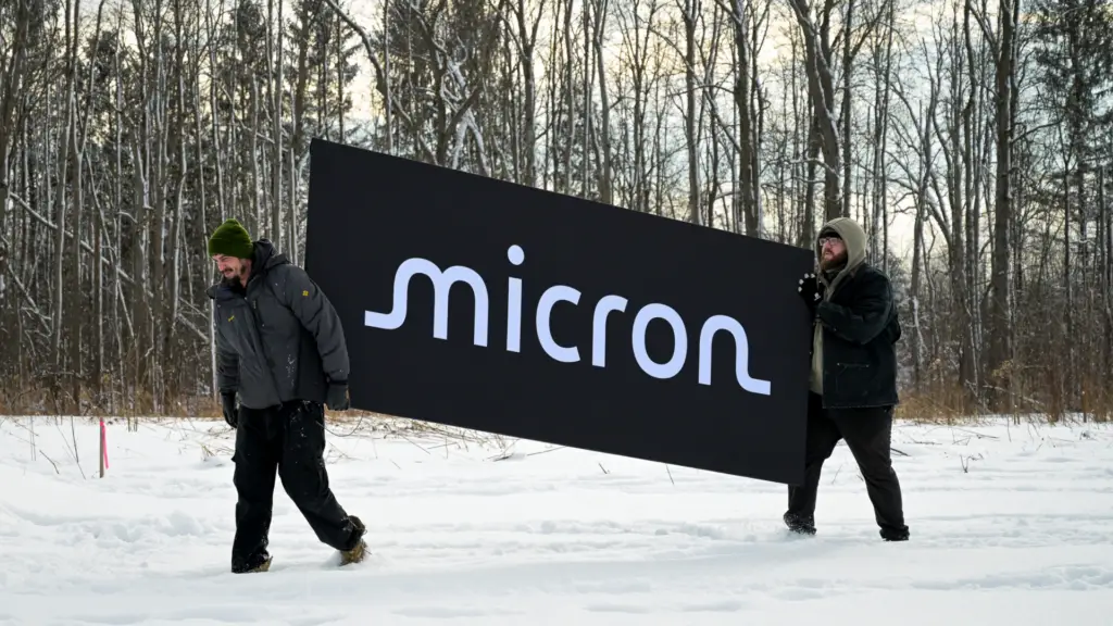 Workers carry a Micron sign during a groundbreaking ceremony for the new Micron Technology Inc. semiconductor manufacturing facility in Clay, New York.