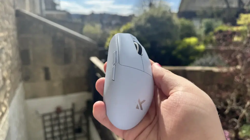 The blue Mchose G3 V2 gaming mouse held in a hand outdoors