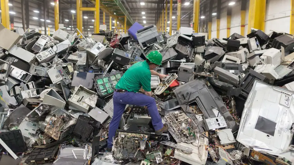 Employee examining electronic waste at a recycling plant.