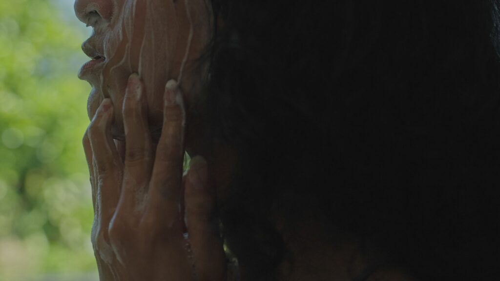 A woman runs fingers down her face, which is covered in foam