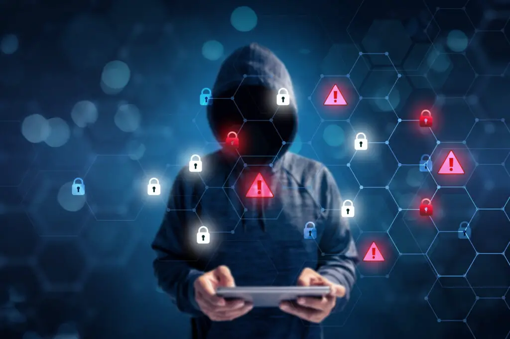 Hacker in a blue hoody standing in front of a coding background