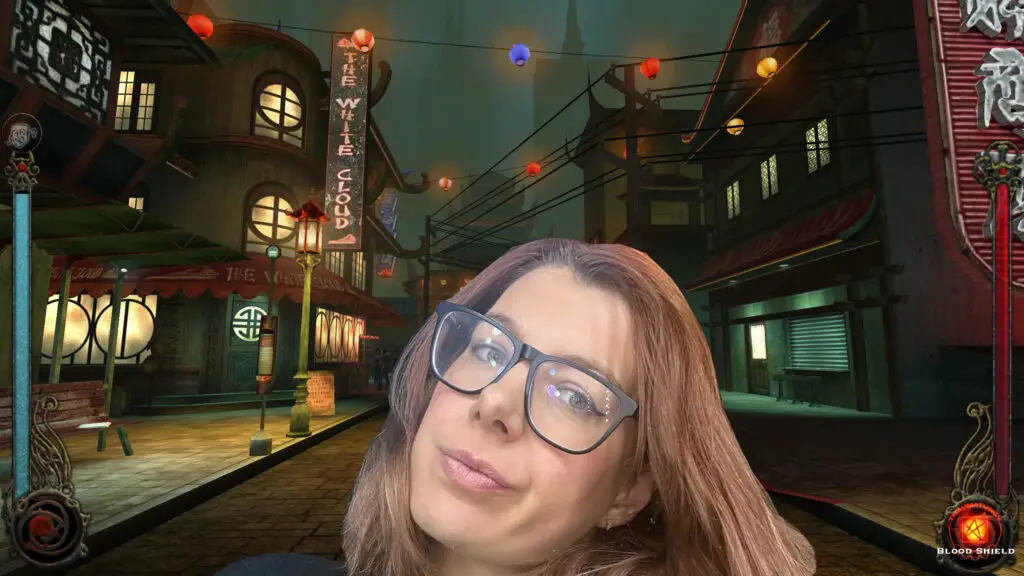 Cara Ellison sitting in front of a monitor showing a Vampire: The Masquerade backdrop